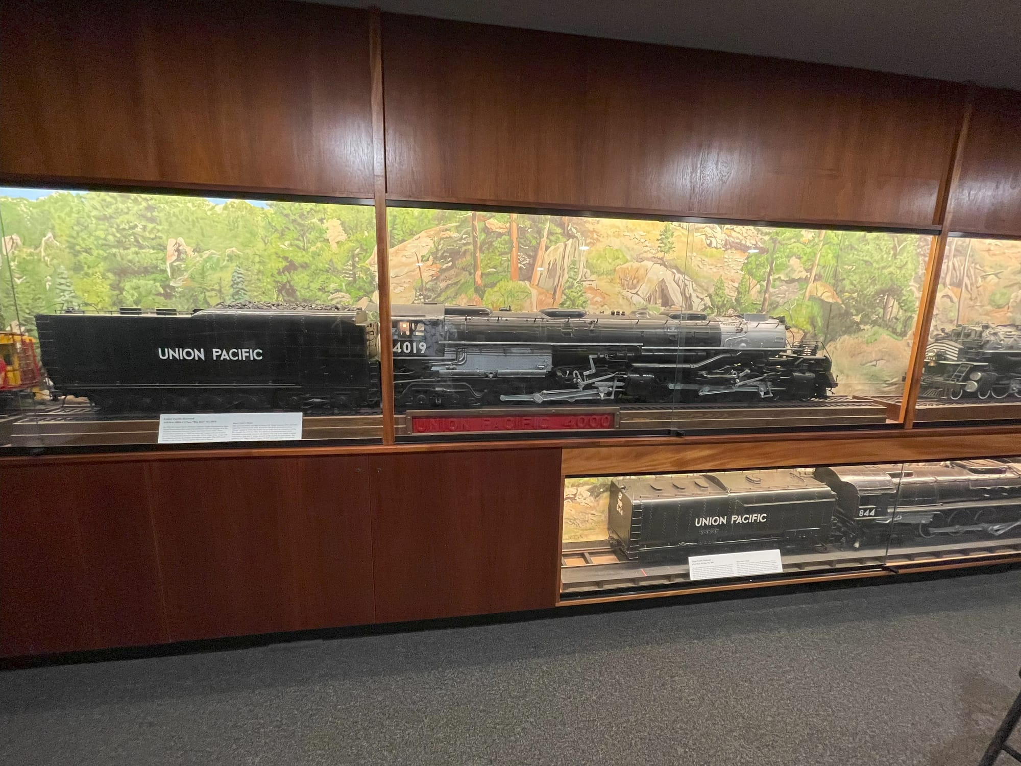 Models of steam locomotives inside a glass case. The main image is on Big Boy #4019. UP #844 is below it