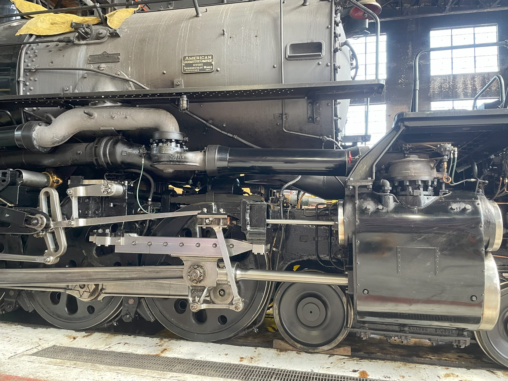 front side view of Big Boy 4014 steam locomotive. The silver boiler is visible with the builder plate above pipes, rods, and the black and silver pistons