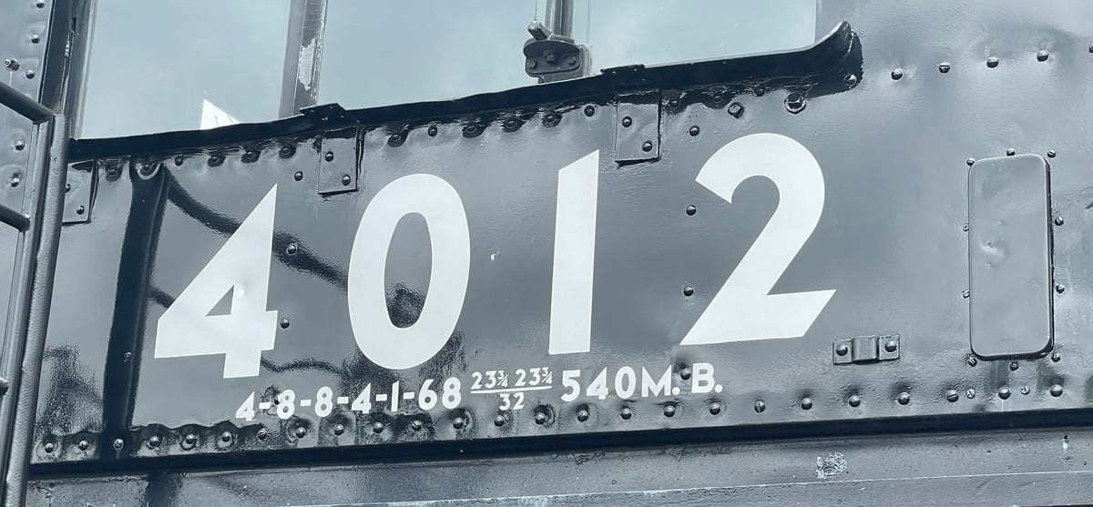 The cab of a black steam locomotive. The number in white is 4012 under a glass window. The rivets are visible in two rows running left and right, above and below the numbers.